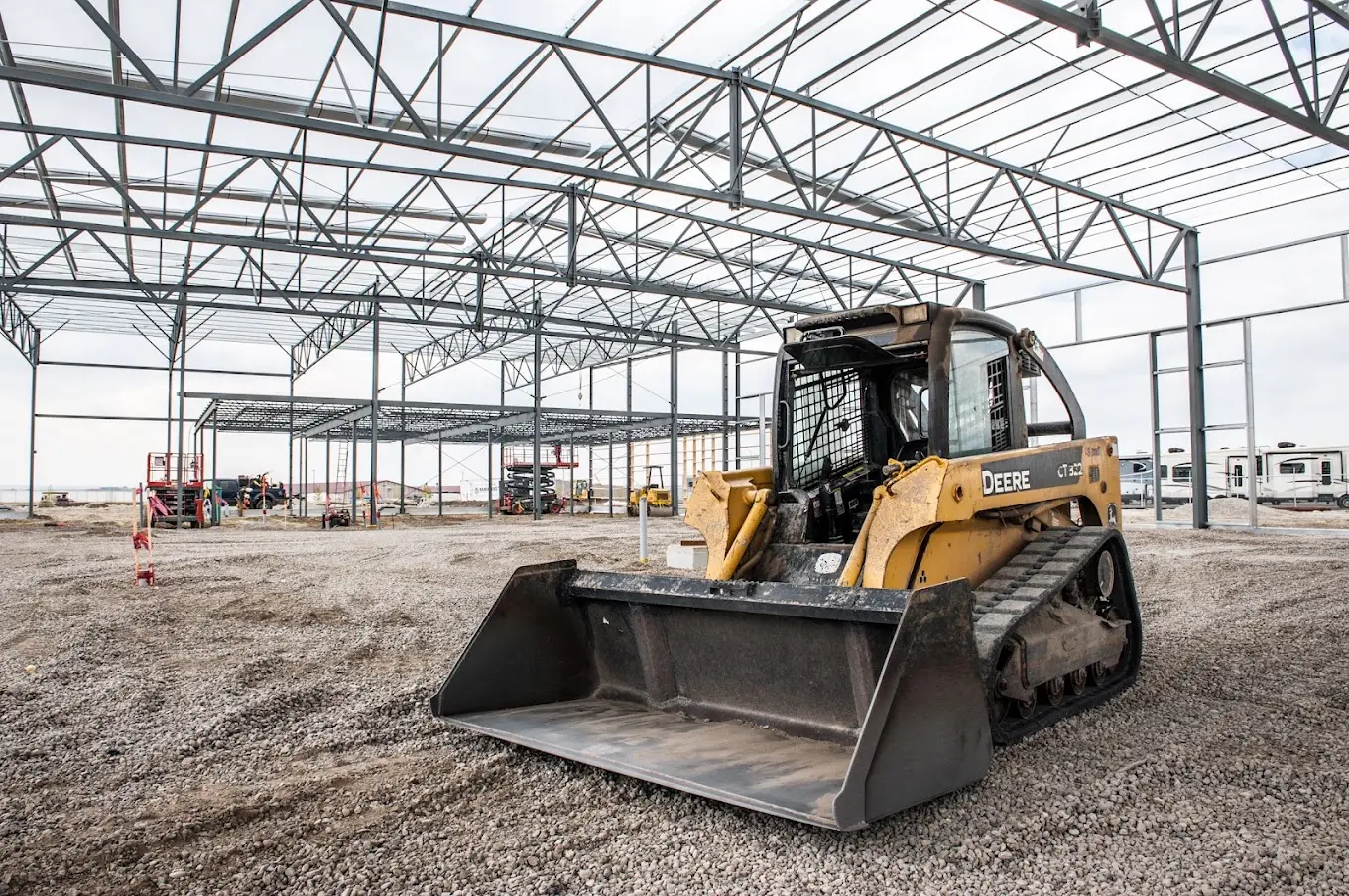 Compacted gravel base inside a completed clear-span steel frame, ready for the slab
