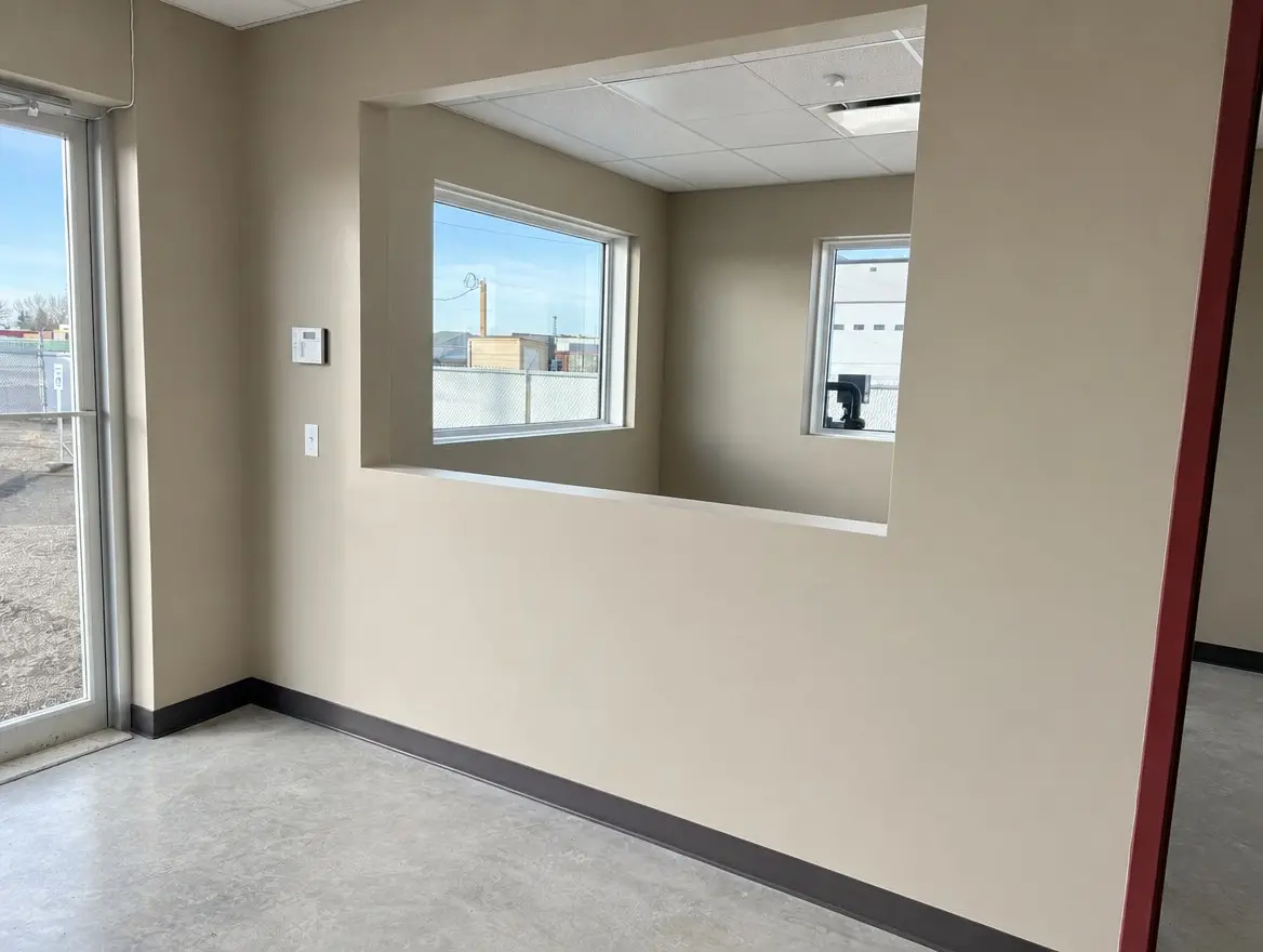 Office reception room with a pass-through window to the next room, exterior windows, a glass door and polished concrete floor